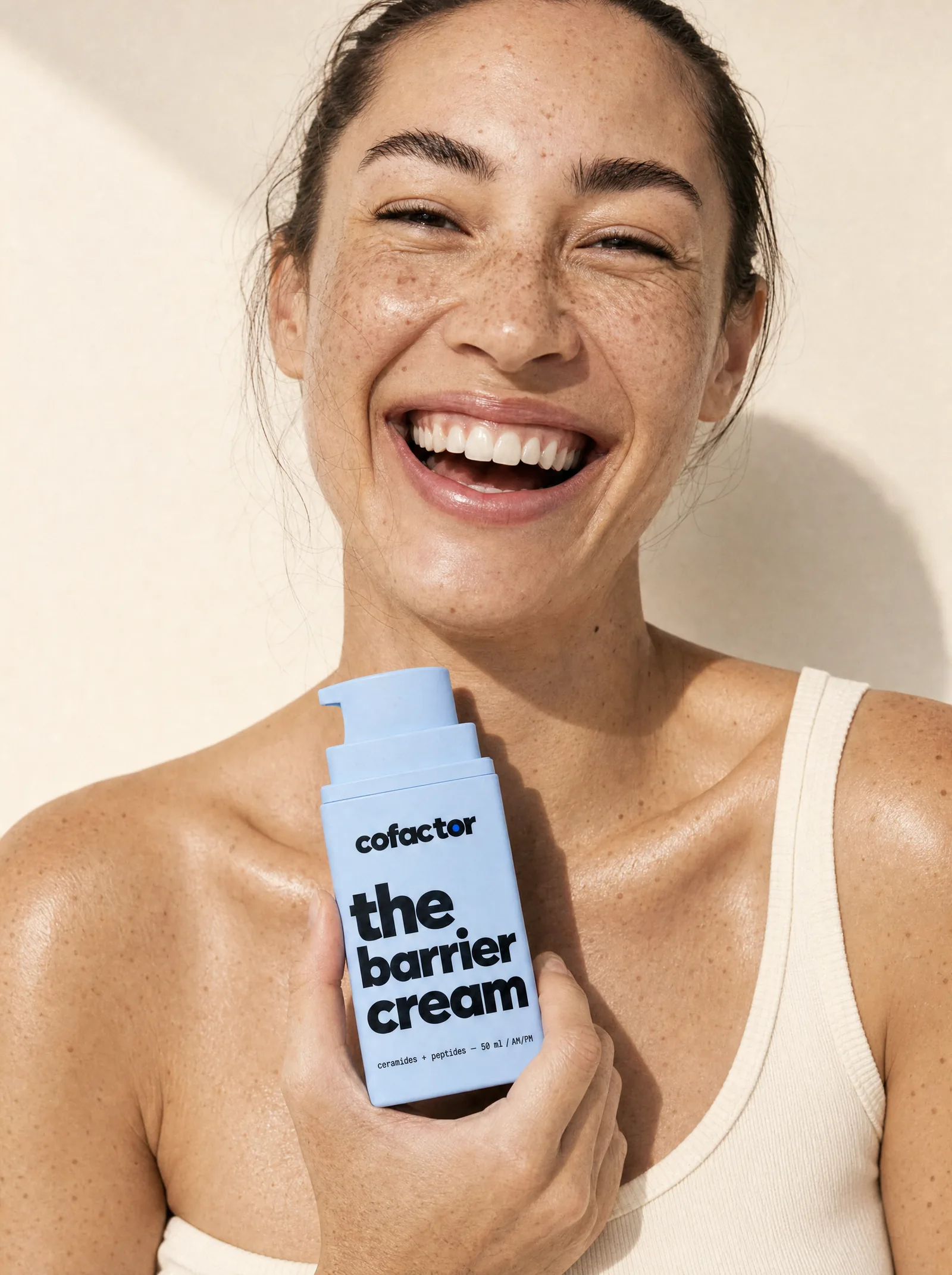 a woman laughing in hard sun, holding the barrier cream